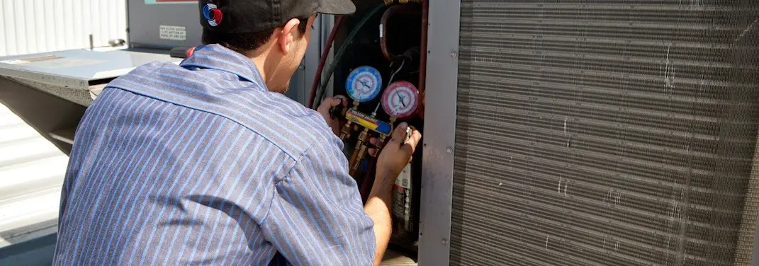HVAC technician servicing a condenser unit in Grandview